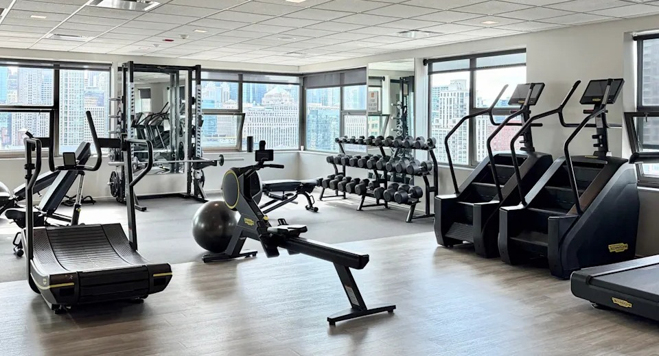 Comprehensive fitness center with a variety of cardio and strength training equipment, offering city views at West77 Apartments, Chicago