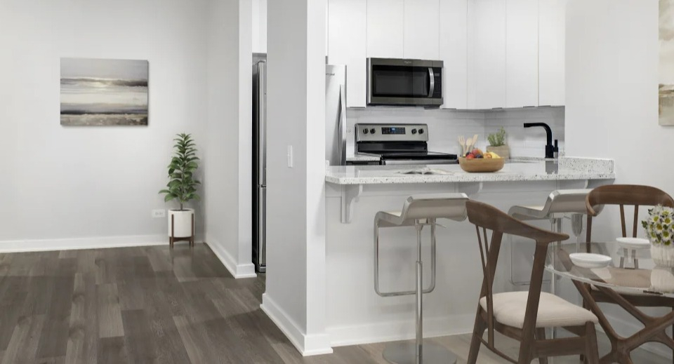 Bright apartment kitchen with white cabinets, a breakfast bar, and an adjacent dining area at West77 Apartments in Chicago