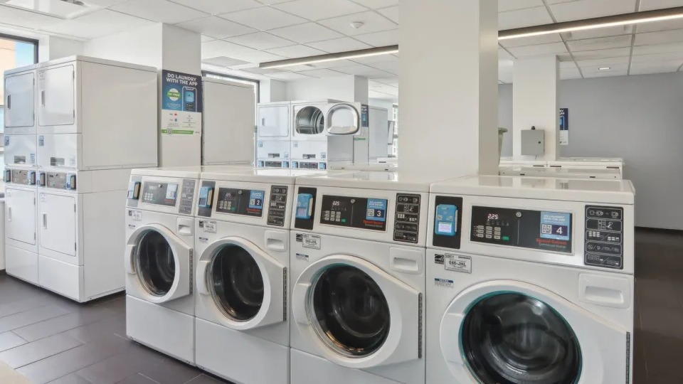 Modern and well-lit communal laundry room with multiple high-efficiency washers and dryers at West77 Apartments in Chicago