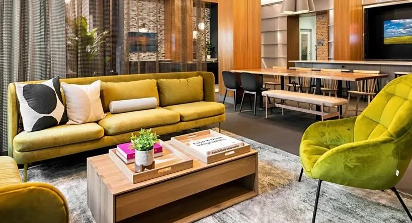 Vibrant resident lounge with comfortable yellow sofas, a large wooden table, and modern decor, perfect for socializing at West77, Chicago