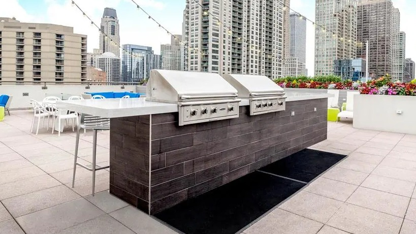 Expansive rooftop deck with grilling stations, outdoor seating, and panoramic Chicago skyline views at West77 Apartments