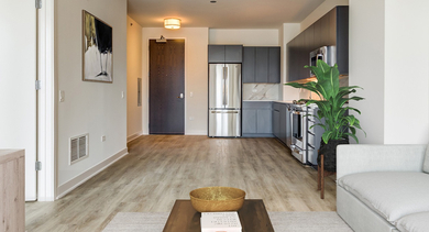 Open-concept apartment featuring a bright living room and a modern kitchen with sleek cabinetry and hardwood floors at Westerly, Chicago