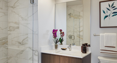 Elegant bathroom with a spacious walk-in shower, modern vanity, and sleek marble-patterned tiles at Westerly Apartments in Chicago