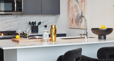 Detailed view of a modern kitchen island with black bar stools, a stylish faucet, and white marble backsplash at Westerly, Chicago