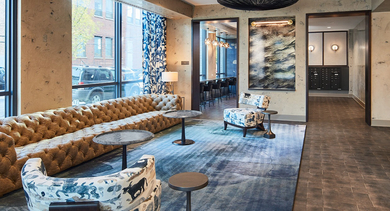 Eclectic lobby lounge with a long tufted sofa, patterned chairs, and unique decor elements, creating a vintage-modern feel at Westerly, Chicago