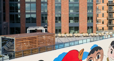 Unique rooftop area with lounge chairs, shaded pergolas, and a colorful mural, offering outdoor relaxation at Westerly, Chicago