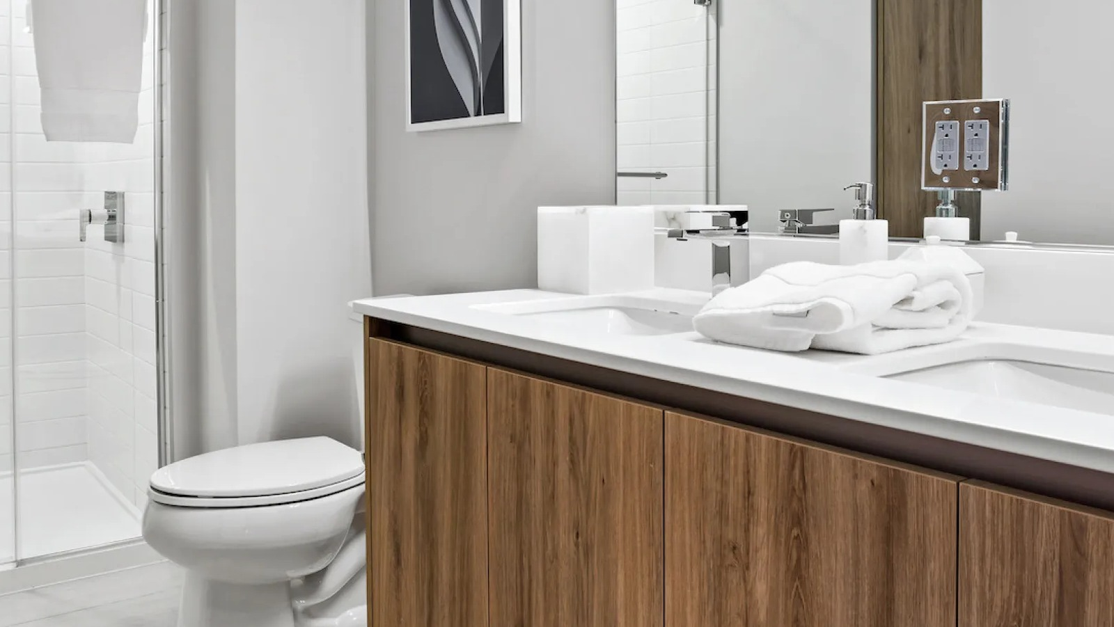 Contemporary bathroom with a double vanity, large mirror, and a spacious walk-in shower at Wolf Point East apartments in Chicago