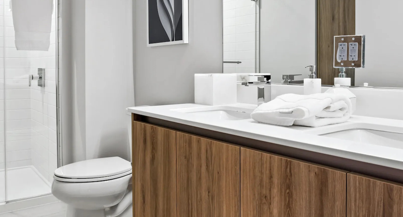 Contemporary bathroom with a double vanity, large mirror, and a spacious walk-in shower at Wolf Point East apartments in Chicago