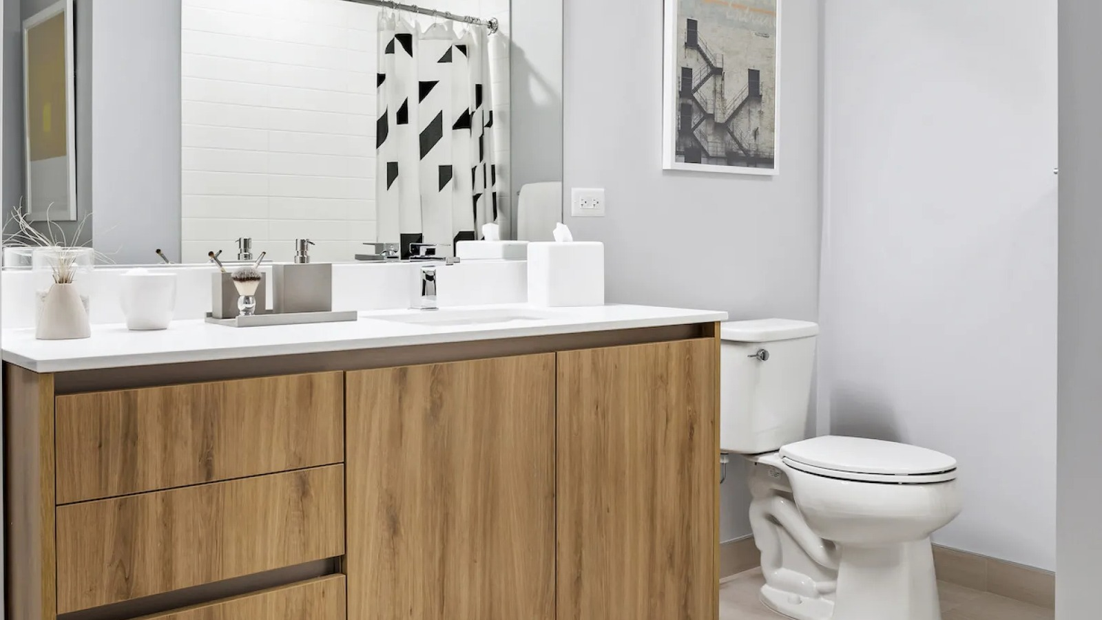 Modern bathroom featuring a stylish wooden vanity, white toilet, and a geometric shower curtain at Wolf Point East in Chicago
