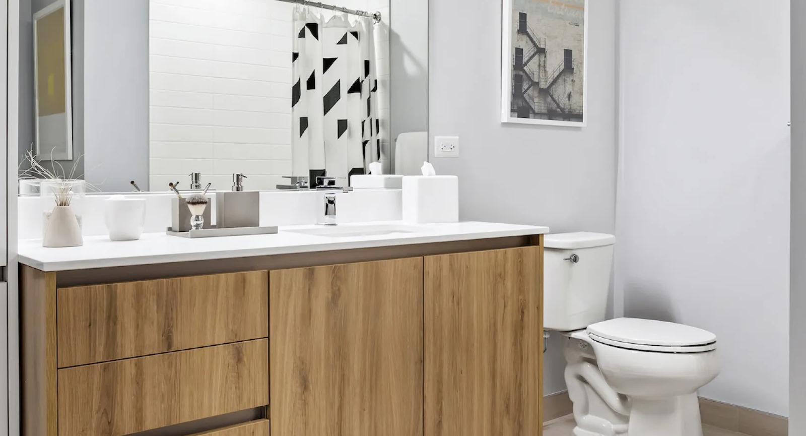 Modern bathroom featuring a stylish wooden vanity, white toilet, and a geometric shower curtain at Wolf Point East in Chicago