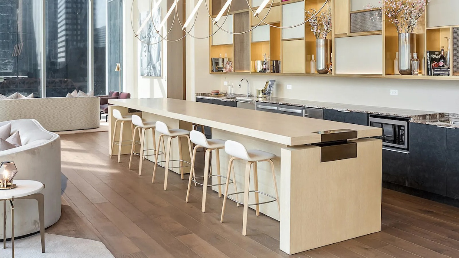 Elegant communal kitchen and lounge area with a long island, bar stools, and city views at Wolf Point East apartments in Chicago