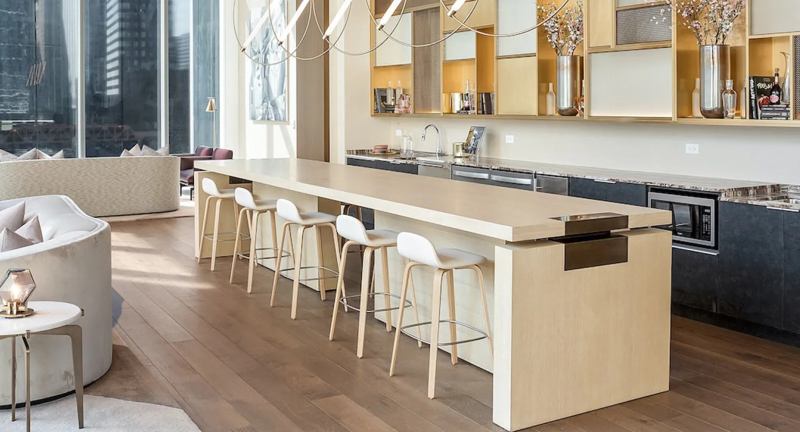 Elegant communal kitchen and lounge area with a long island, bar stools, and city views at Wolf Point East apartments in Chicago