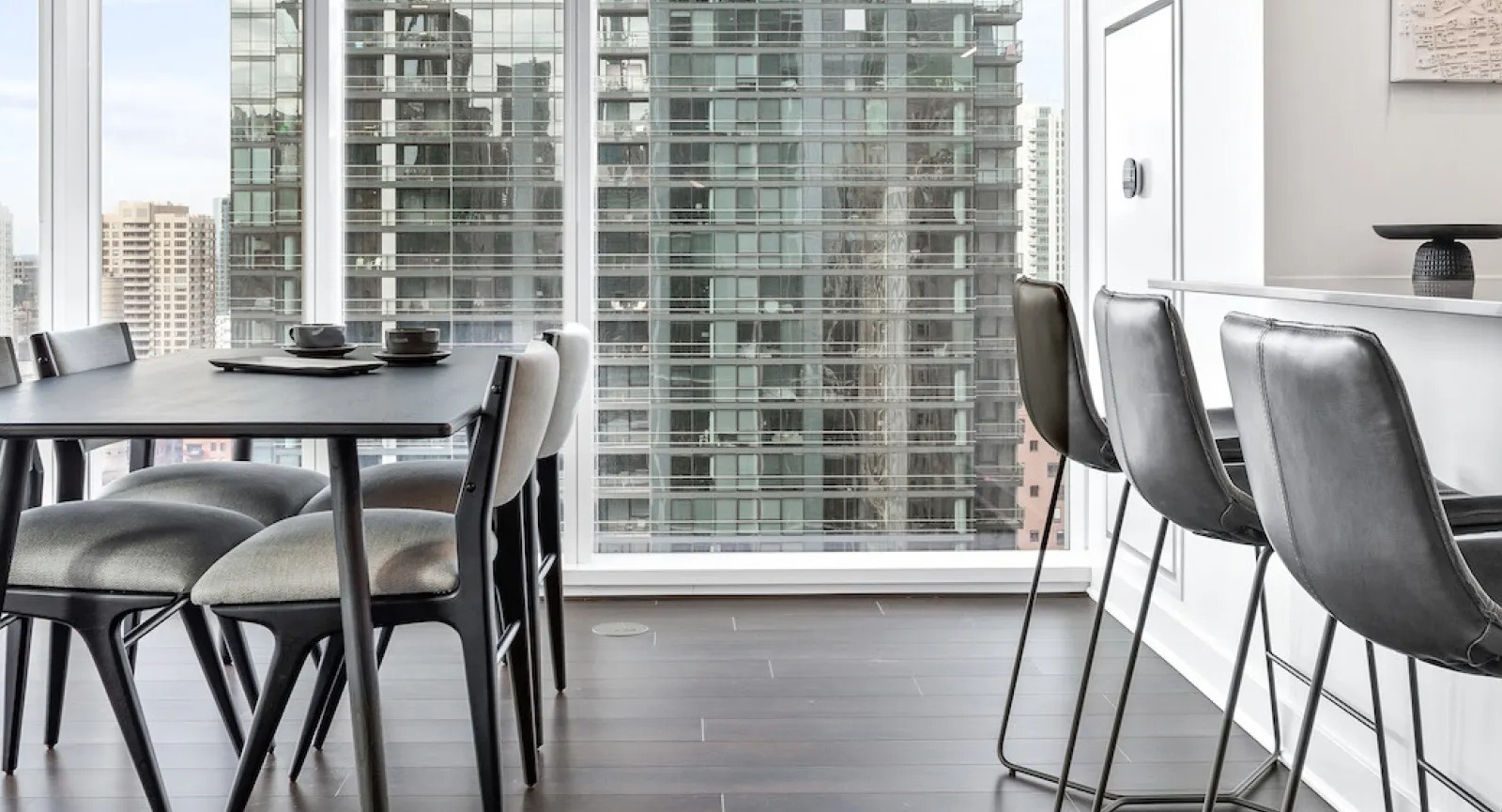 Modern dining area with a black table and chairs, offering panoramic city views from Wolf Point East apartments in Chicago