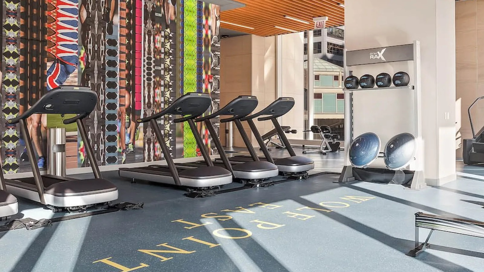 Modern fitness center with treadmills, rowing machines, and colorful wall art at Wolf Point East apartments in Chicago