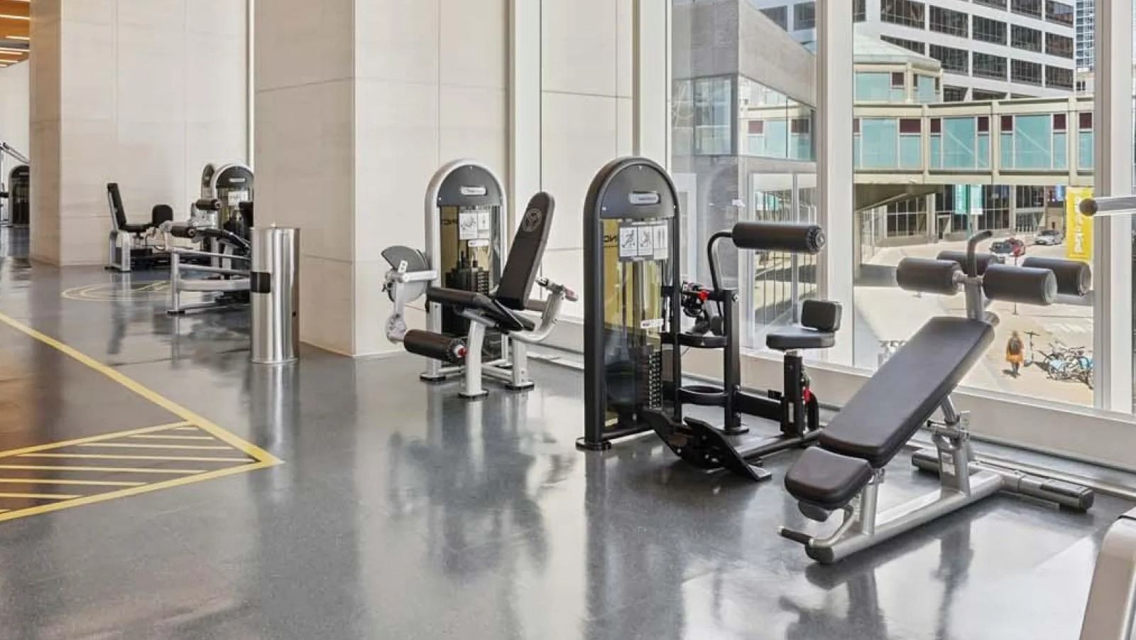 Bright fitness center featuring a variety of weight machines and large windows overlooking the city at Wolf Point East in Chicago