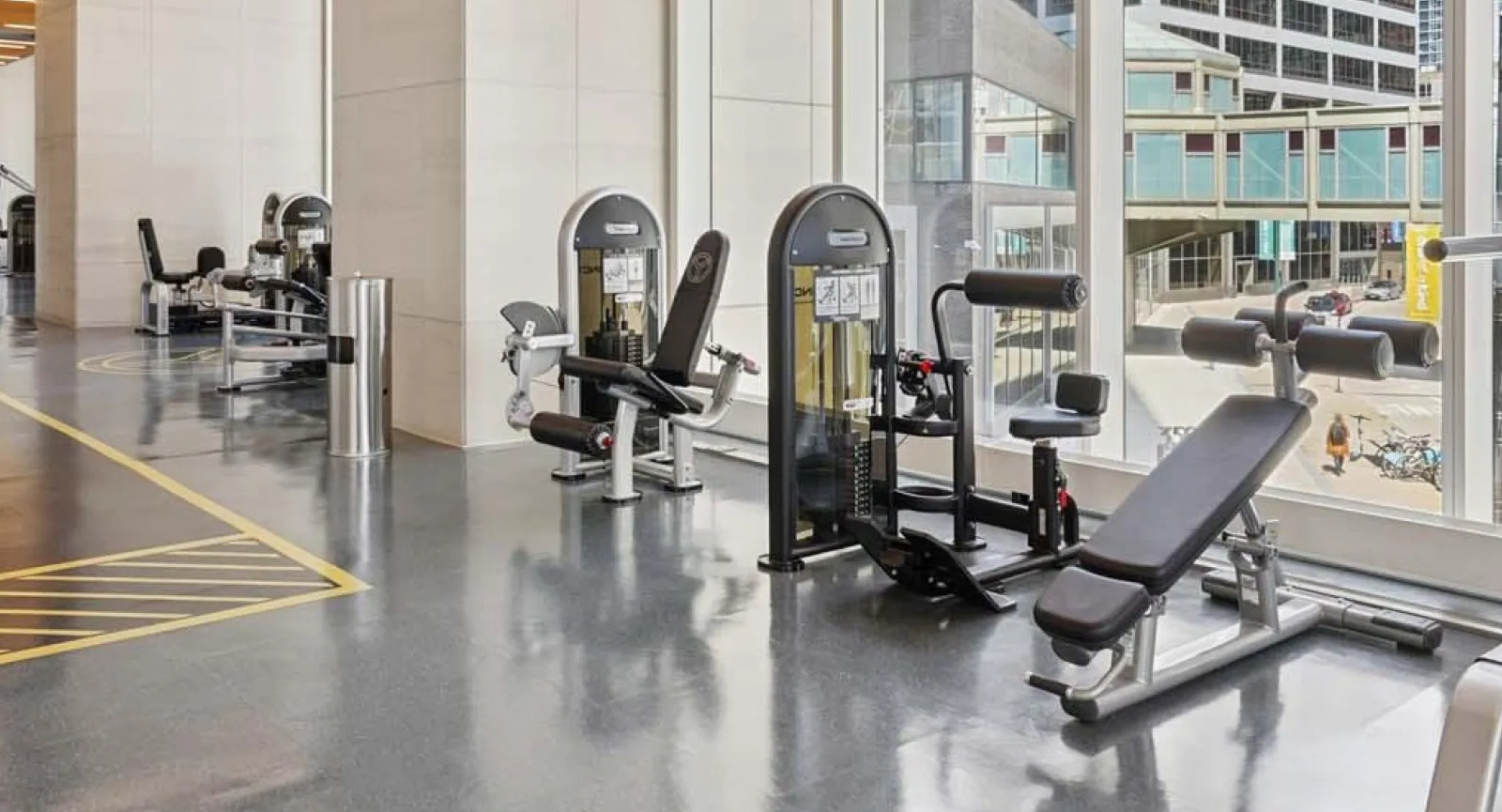 Bright fitness center featuring a variety of weight machines and large windows overlooking the city at Wolf Point East in Chicago