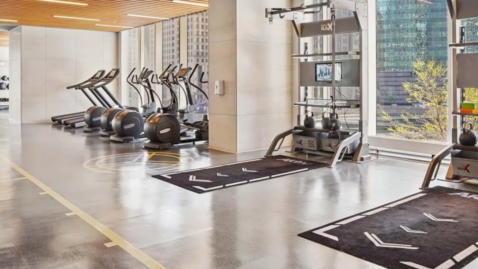 Spacious gym area with free weights, cardio machines, and large windows at Wolf Point East apartments in Chicago