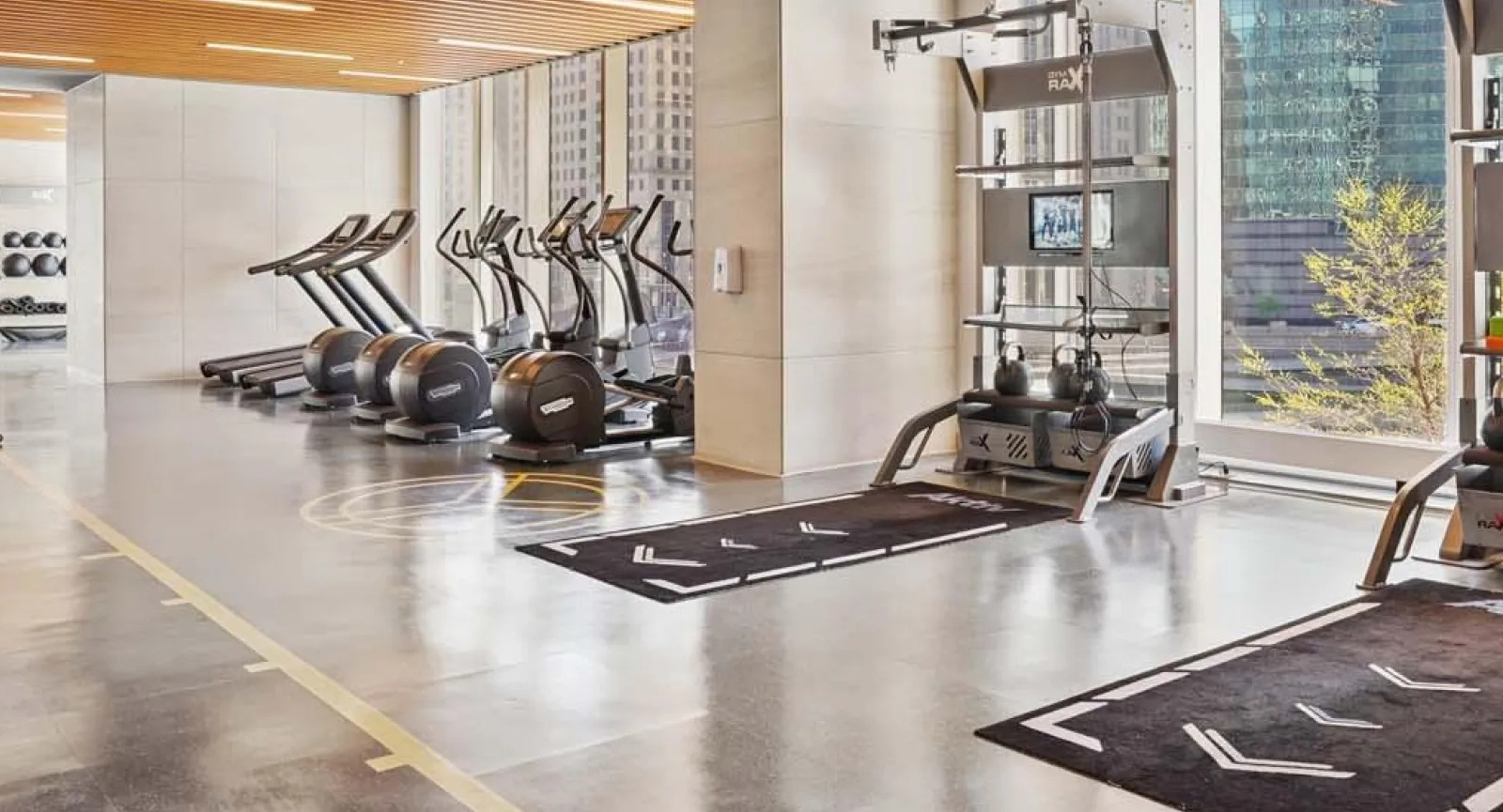Spacious gym area with free weights, cardio machines, and large windows at Wolf Point East apartments in Chicago