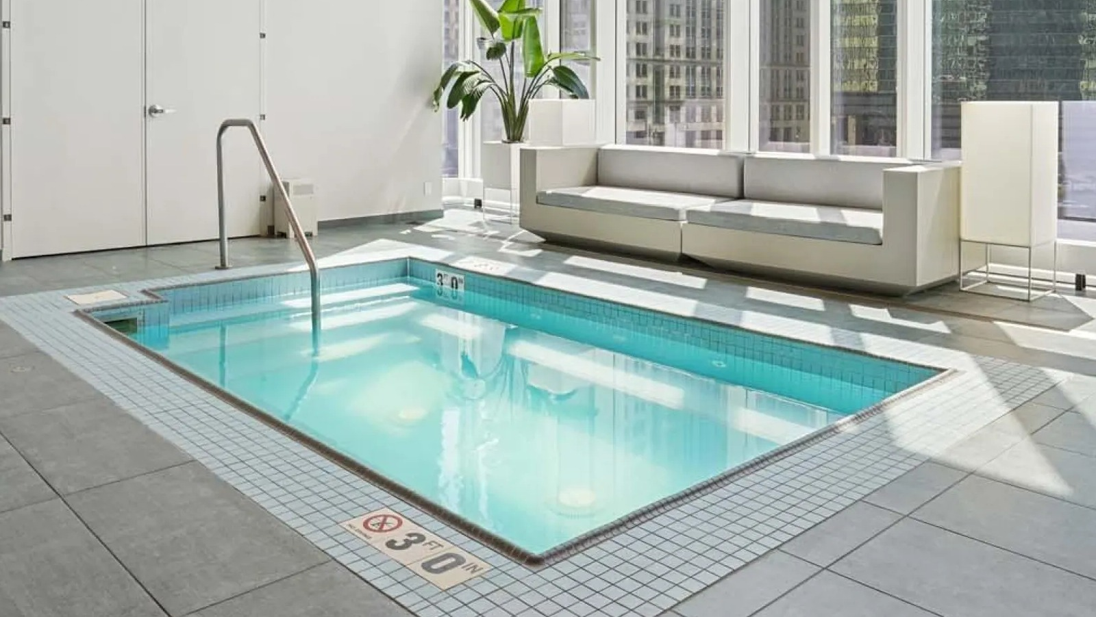 Serene indoor pool area with large windows offering panoramic city views and comfortable seating at Wolf Point East in Chicago