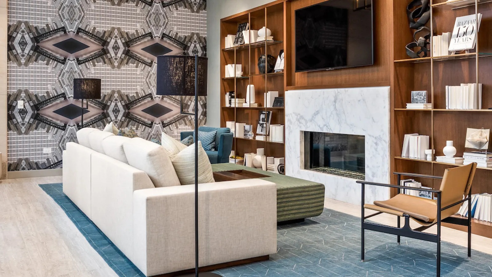 Modern living room with stylish furniture, a large TV, fireplace, and unique geometric wallpaper at Wolf Point East in Chicago