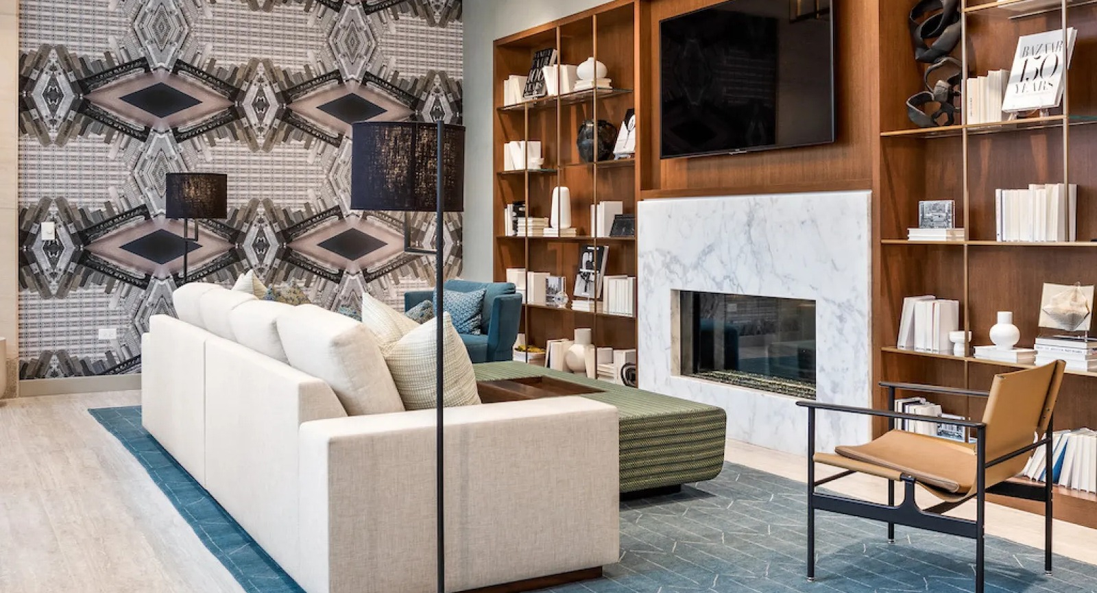 Modern living room with stylish furniture, a large TV, fireplace, and unique geometric wallpaper at Wolf Point East in Chicago