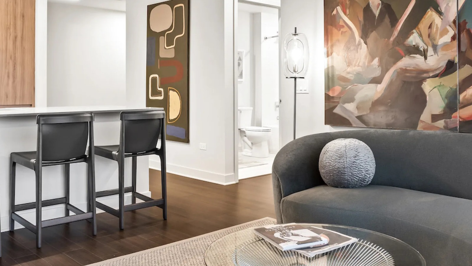 Elegant living space with a curved sofa, glass coffee table, and abstract artwork at Wolf Point East apartments in Chicago