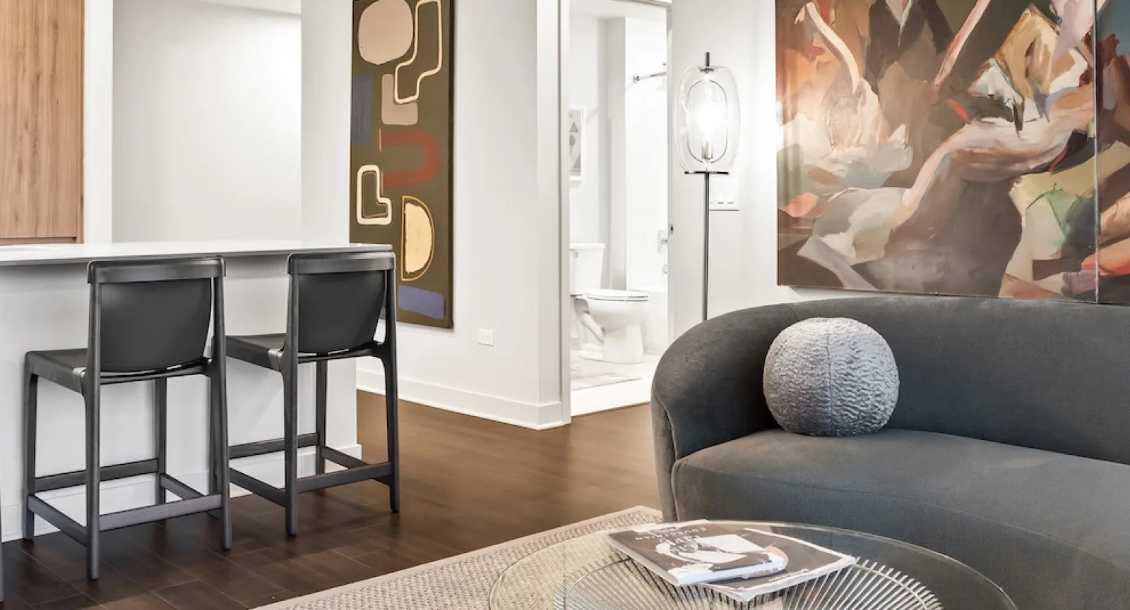 Elegant living space with a curved sofa, glass coffee table, and abstract artwork at Wolf Point East apartments in Chicago