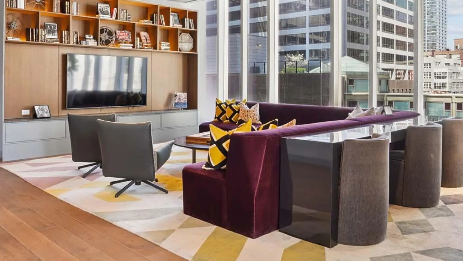 Modern co-working lounge with stylish seating, a large screen, and city views at Wolf Point East apartments in Chicago