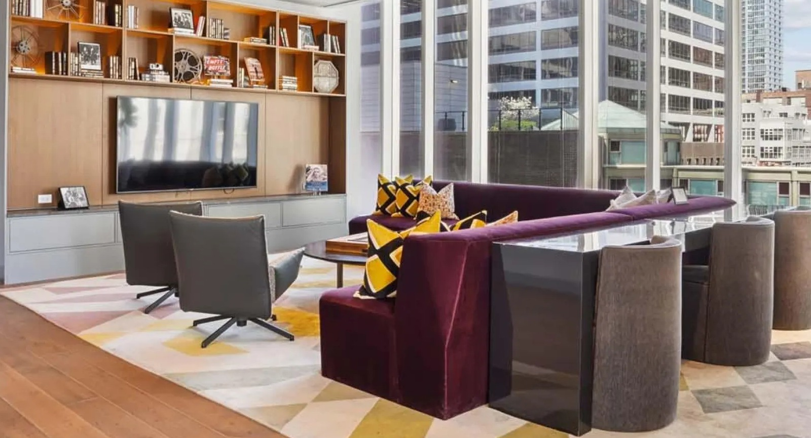 Modern co-working lounge with stylish seating, a large screen, and city views at Wolf Point East apartments in Chicago