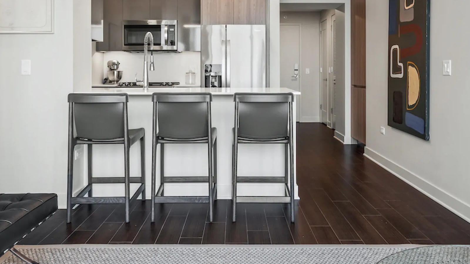 Modern open-concept kitchen and living area featuring stylish bar seating and contemporary art at Wolf Point East in Chicago