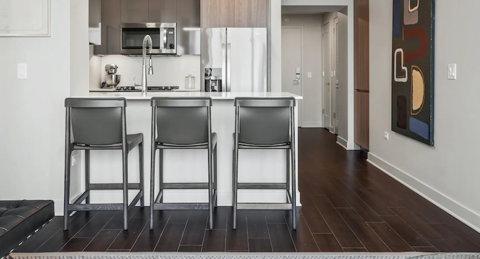 Modern open-concept kitchen and living area featuring stylish bar seating and contemporary art at Wolf Point East in Chicago