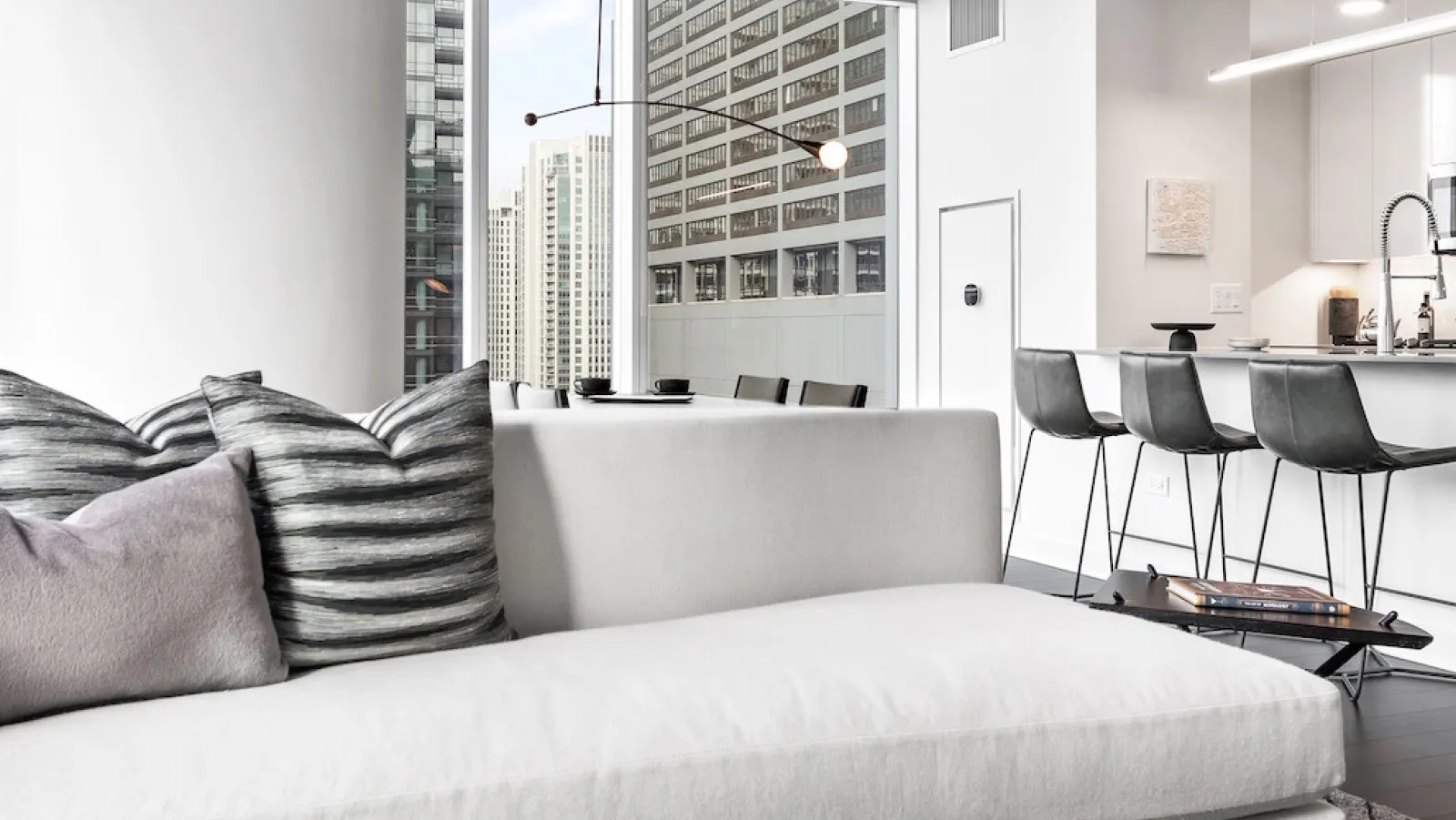 Open concept living room flowing into a modern kitchen, featuring sleek design and city views at Wolf Point East in Chicago