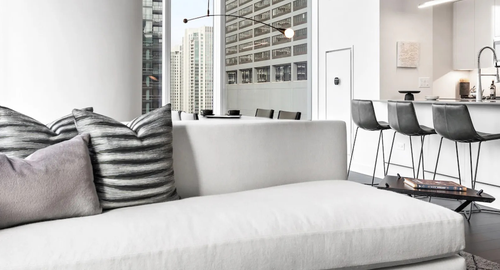 Open concept living room flowing into a modern kitchen, featuring sleek design and city views at Wolf Point East in Chicago