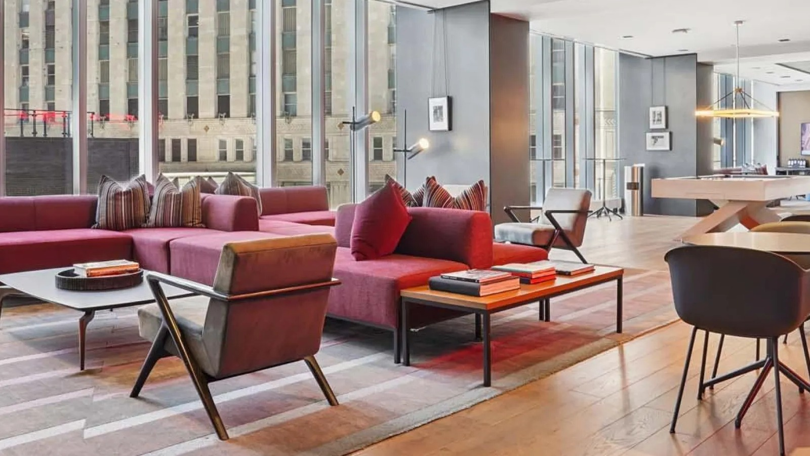 Luxurious resident lounge with modern red sofas, accent chairs, and city views through large windows at Wolf Point East in Chicago