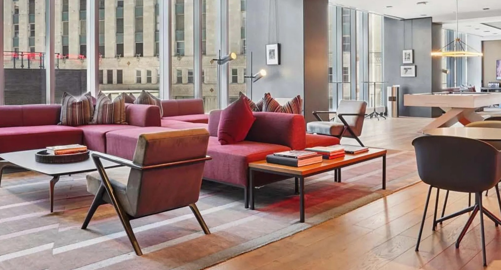 Luxurious resident lounge with modern red sofas, accent chairs, and city views through large windows at Wolf Point East in Chicago