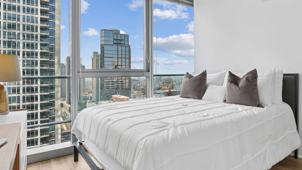 Modern bedroom at Wolf Point West apartments in Chicago with floor-to-ceiling windows and skyline views