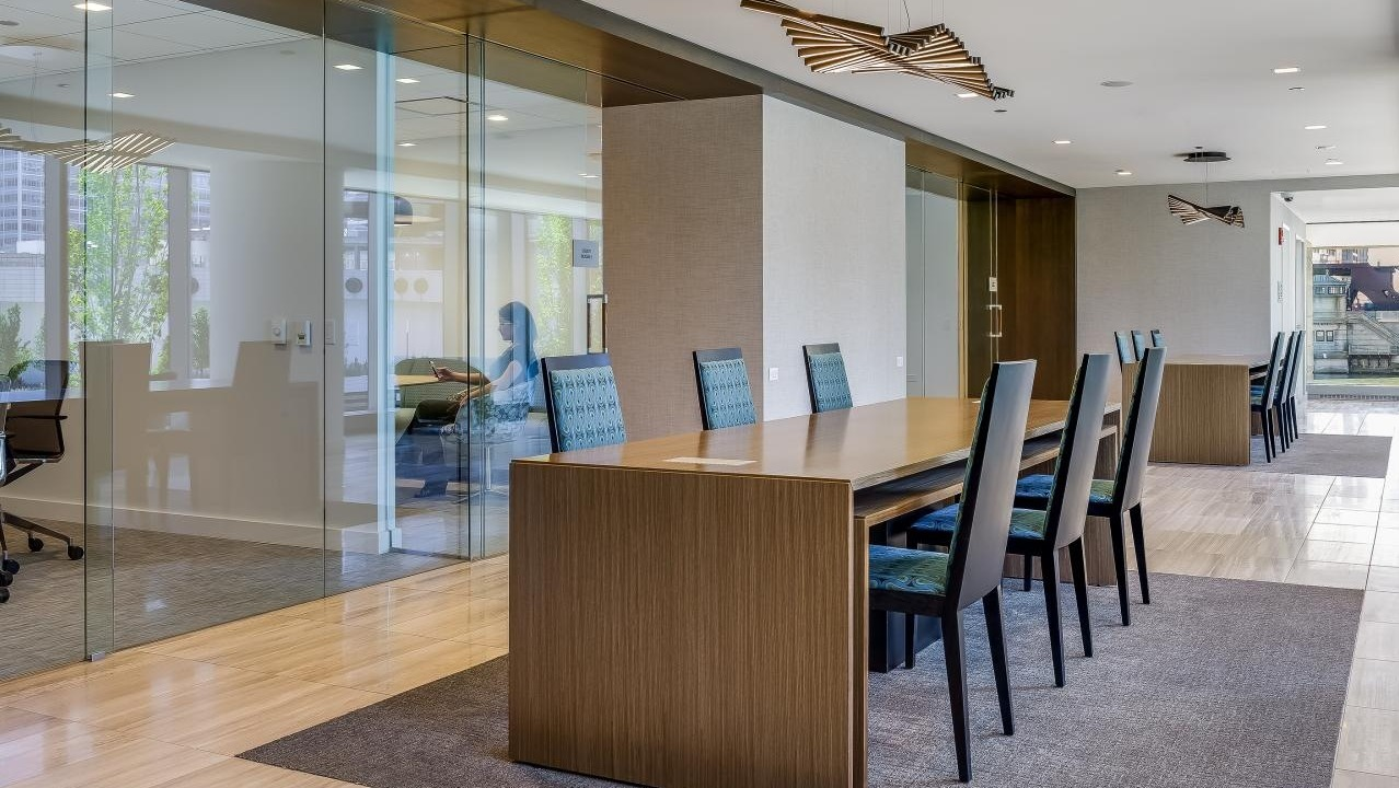 Modern business center at Wolf Point West apartments in Chicago with private offices, long tables, and stylish seating