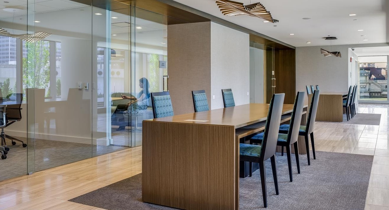 Modern business center at Wolf Point West apartments in Chicago with private offices, long tables, and stylish seating