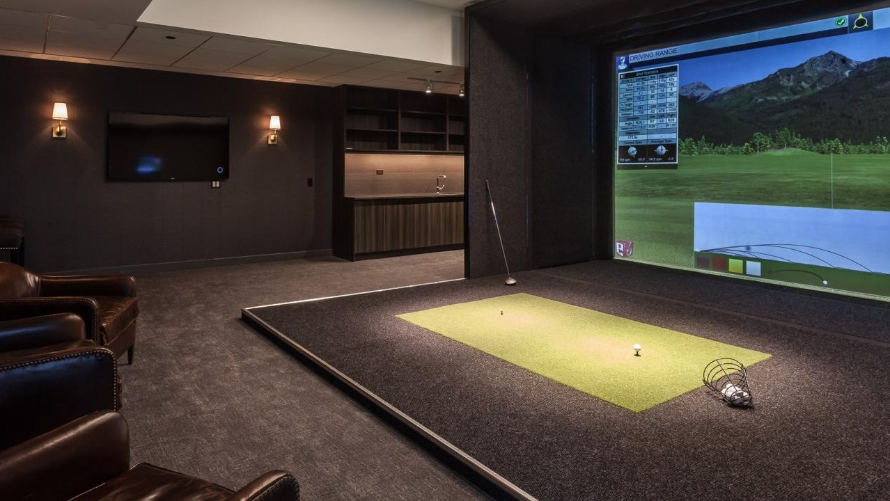 Golf simulator lounge at Wolf Point West apartments in Chicago with leather seating, lounge area, and driving range screen