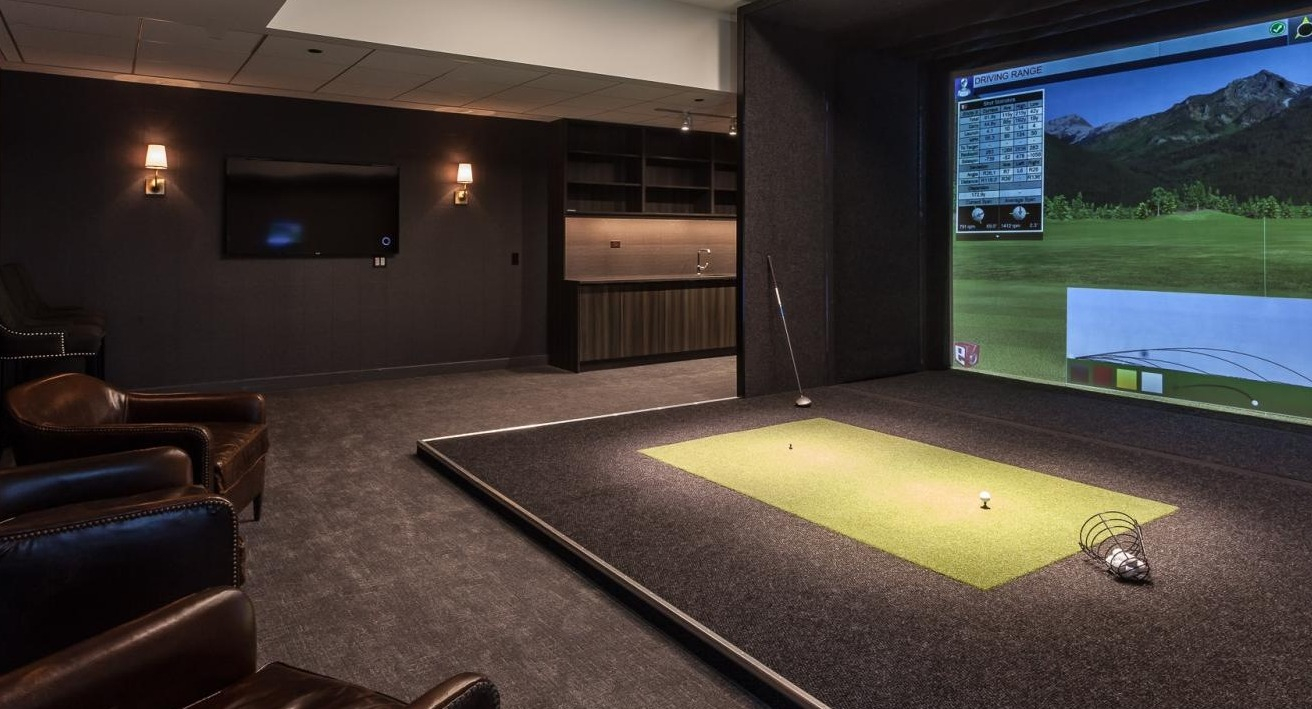 Golf simulator lounge at Wolf Point West apartments in Chicago with leather seating, lounge area, and driving range screen