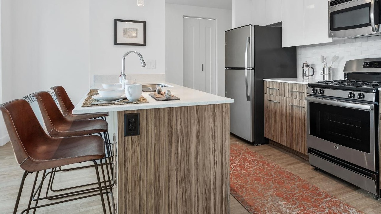 Contemporary kitchen at Wolf Point West apartments in Chicago with breakfast bar seating and stylish wood finishes