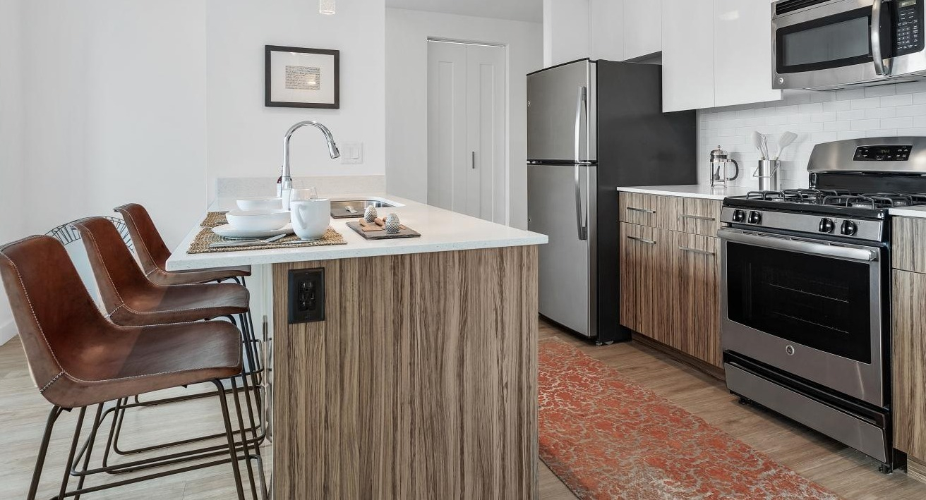 Contemporary kitchen at Wolf Point West apartments in Chicago with breakfast bar seating and stylish wood finishes