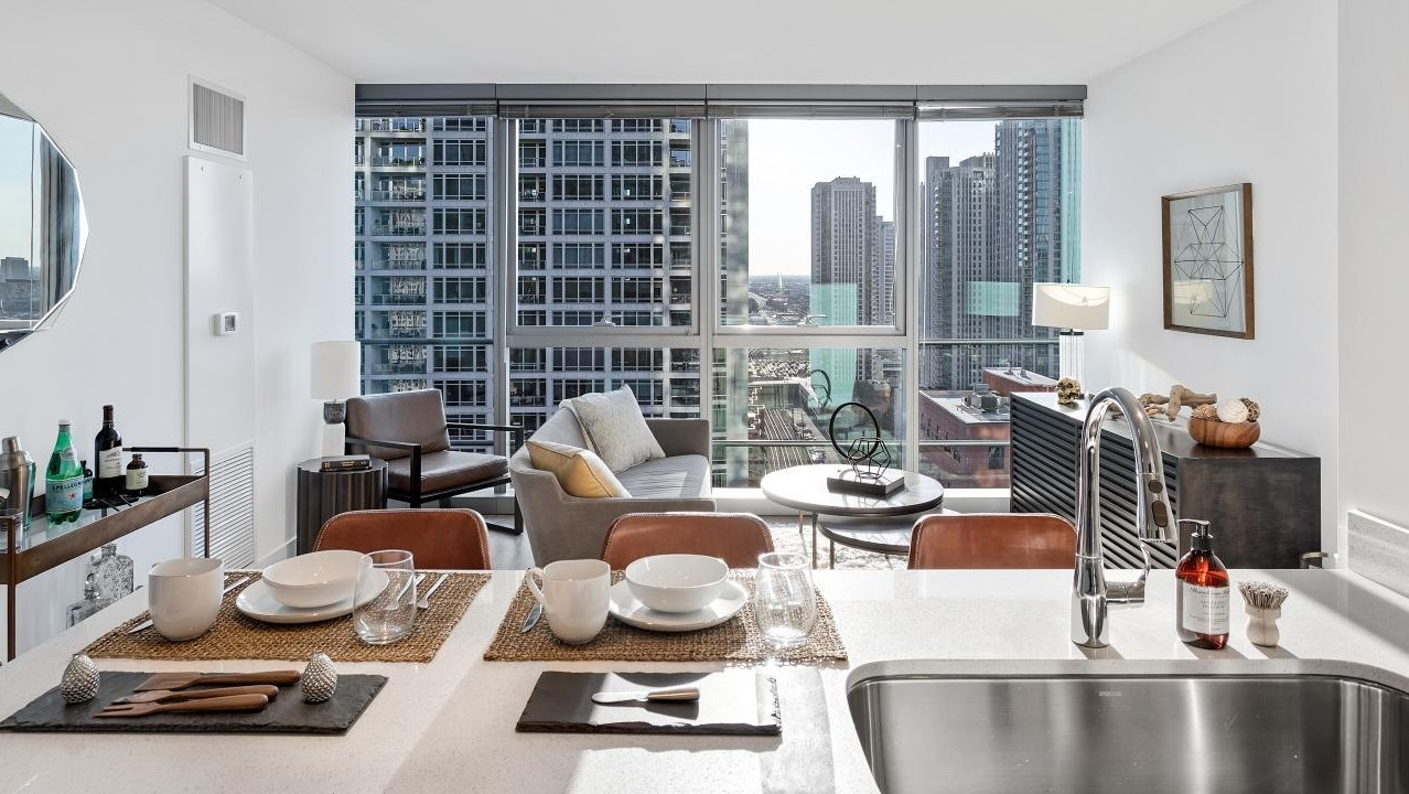 Stylish open kitchen and dining space at Wolf Point West apartments in Chicago featuring modern finishes and skyline views