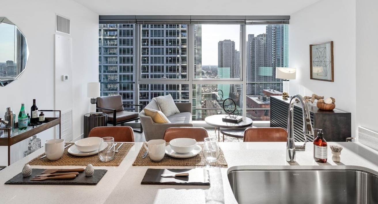 Stylish open kitchen and dining space at Wolf Point West apartments in Chicago featuring modern finishes and skyline views