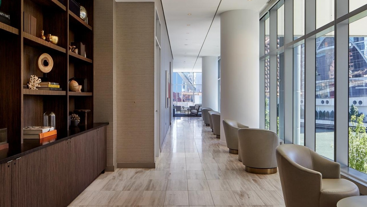Library lounge at Wolf Point West apartments in Chicago with modern shelving, decorative displays, and cozy seating