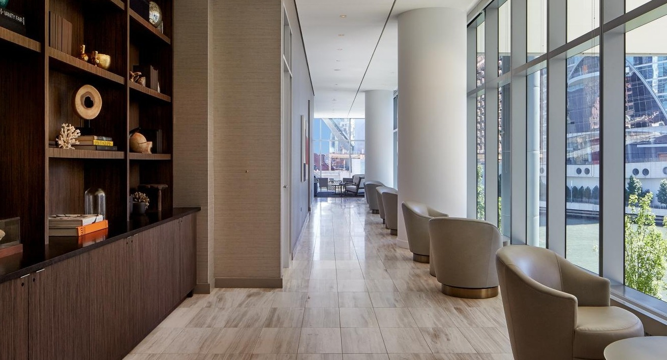 Library lounge at Wolf Point West apartments in Chicago with modern shelving, decorative displays, and cozy seating
