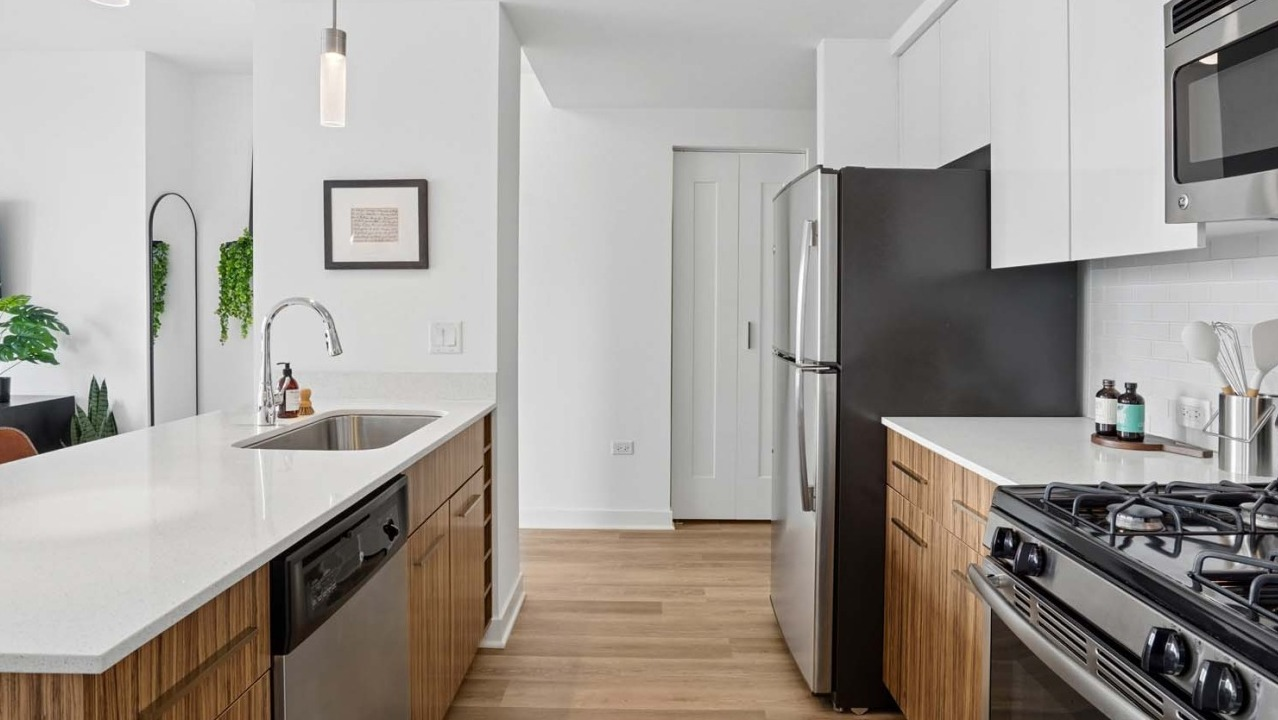 Sleek modern kitchen at Wolf Point West apartments in Chicago with stainless steel appliances and wood cabinetry
