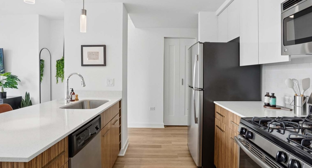 Sleek modern kitchen at Wolf Point West apartments in Chicago with stainless steel appliances and wood cabinetry
