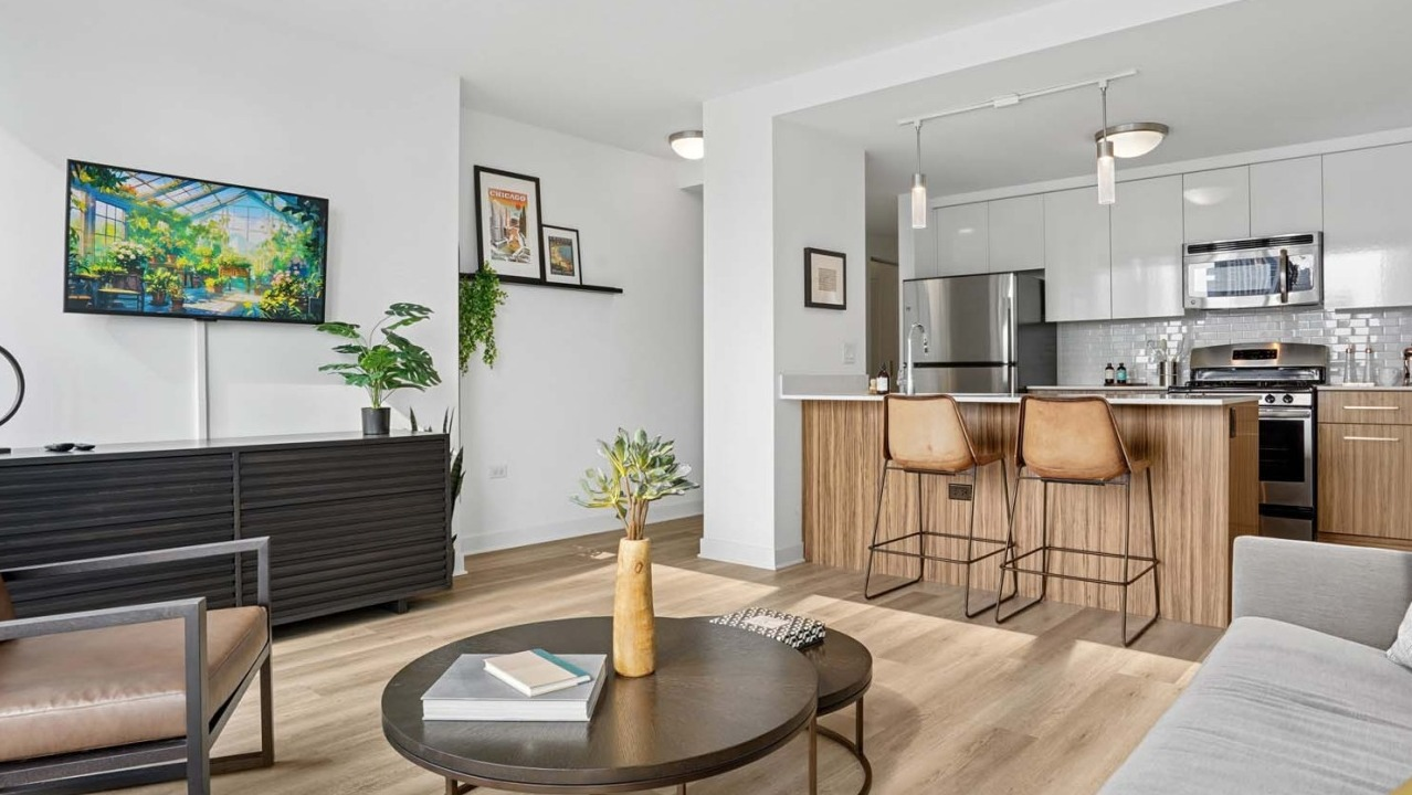Modern living area at Wolf Point West apartments in Chicago with open kitchen, bar stools, and cozy furniture