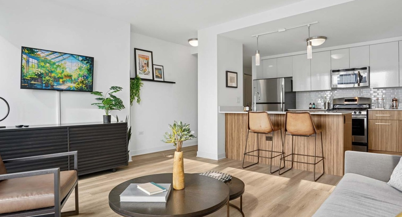Modern living area at Wolf Point West apartments in Chicago with open kitchen, bar stools, and cozy furniture